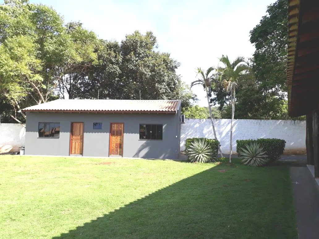 Fachada das suítes do Espaço ToaToa: construção cinza com telhado de barro, portas de madeira e ar-condicionado, de frente para o gramado